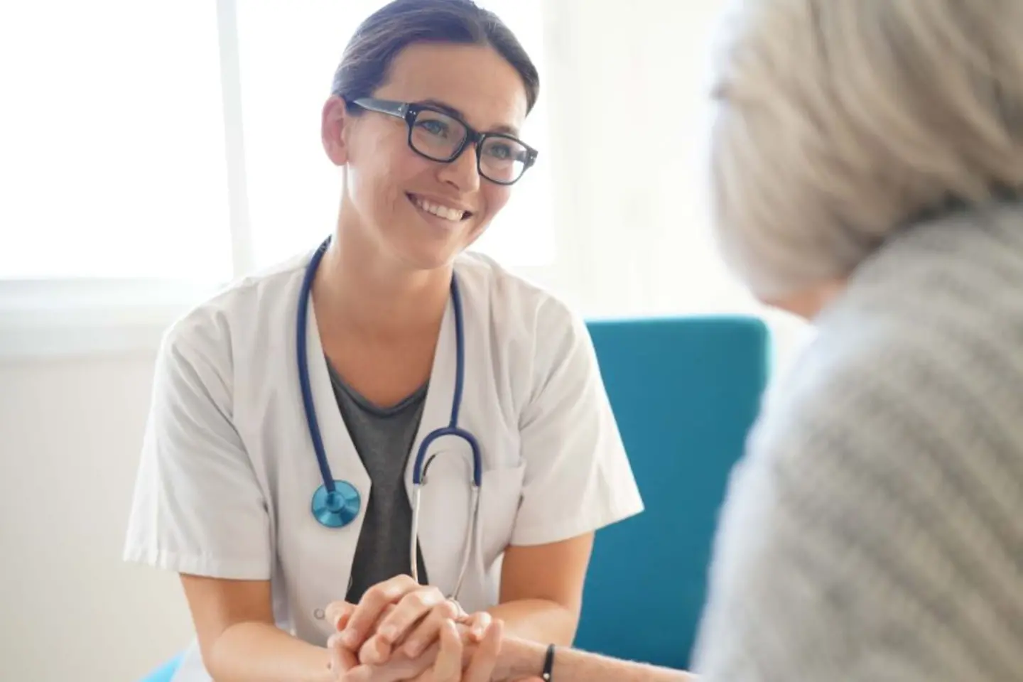 Médica sonriendo cogiendo de la mano a una paciente anciana, servicios nativos de AWS para mejorar la seguridad