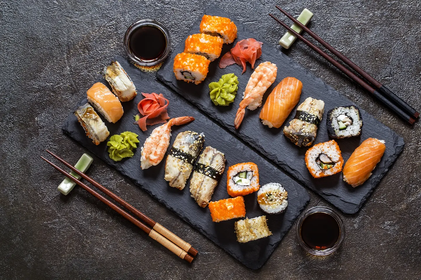 Rollos de sushi con arroz, pescado y salsa de soja sobre fondo de piedra oscura
