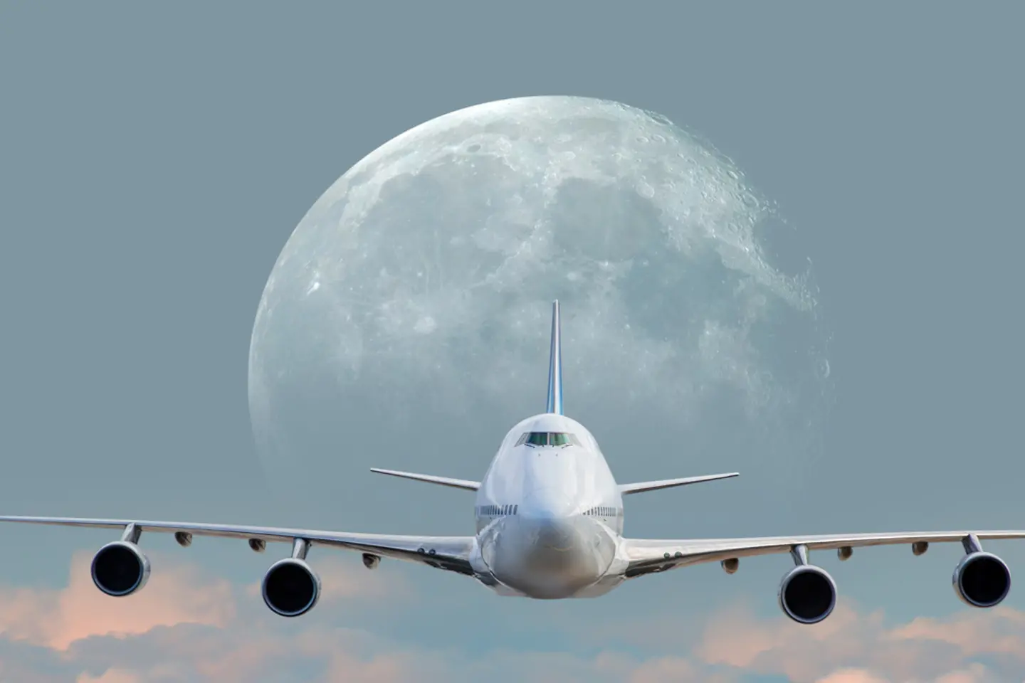 Avión de pasajeros blanco sobre las nubes bajo la luna llena