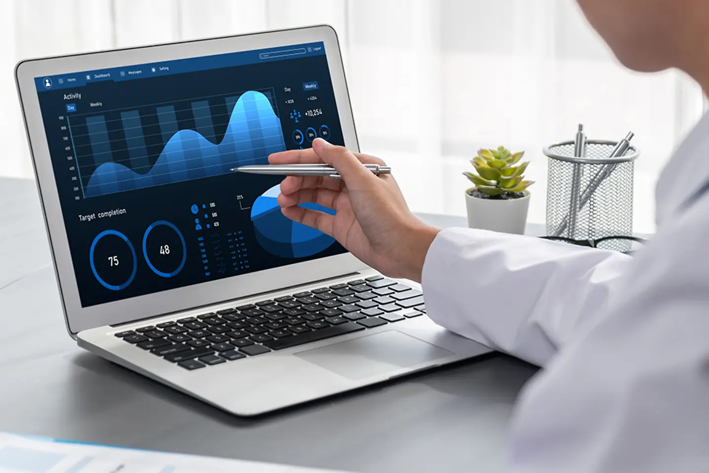 Médica señalando a la pantalla de un laptop con varios diagramas